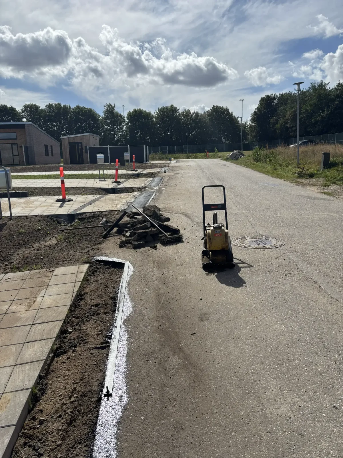 Gul pladevibrator komprimerer ny asfalt ved nyt boligområde